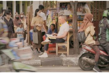 kleurenfoto van presentator Hans Goedkoop zittend op straat in Indonesië