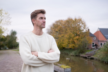 kleurenfoto van presentator Winfried Baijens voor huizen in Groningen met armen over elkaar