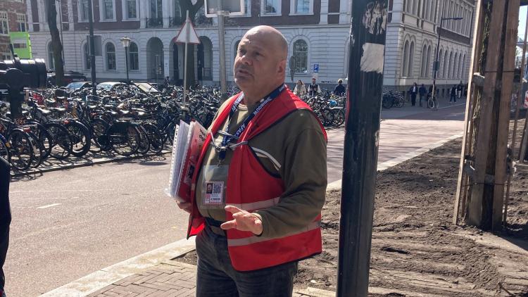 foto van man in rood hesje met daklozenkrant