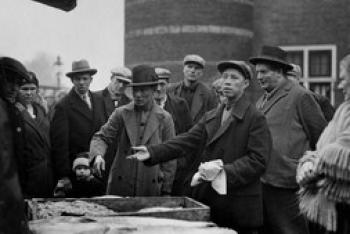 Zwart wit beeld van een aantal mannen met Chinees uiterlijk met hoeden op op een markt.