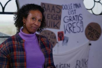 Presentatrice Astrid staat naast posters van Dolle Mina.