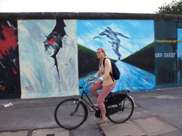 Sanne Boersma fietst langs de East Side Gallery